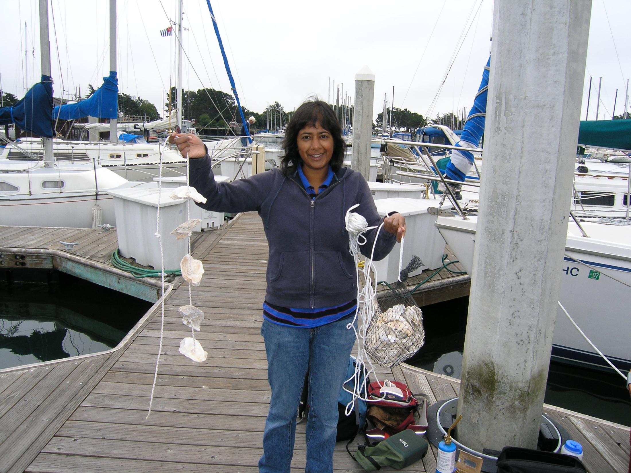 Graduate student holding an oyster recruitment "necklace"